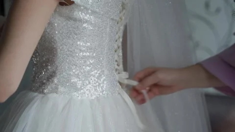A beautiful bride is having her wedding dress tied Stock Footage 306173847