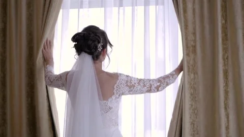 Beautiful bride opens the curtains on window Stock Footage 101154569
