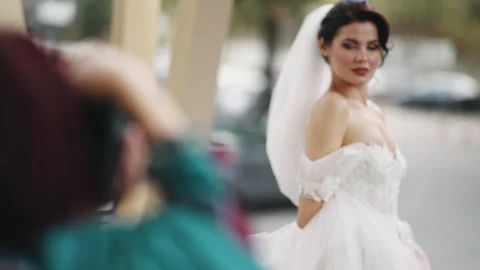 Beautiful bride posing for her wedding photographer outdoors in elegant attir Stock Footage 344703642