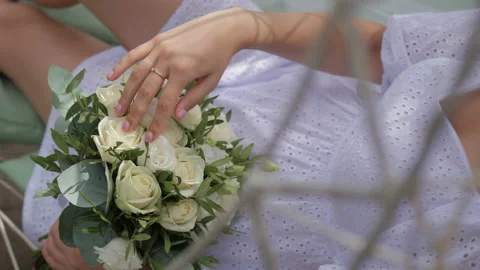 A beautiful bride sits on the grass, looking at her wedding bouquet. Stock Footage 236898882