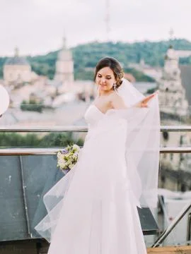 Beautiful bride is sorting the veil while standing near the balcony fence. Foto stock