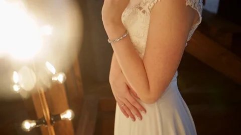 Beautiful bride stands in front of a mirror with lights in a loft interior Stock Footage 69827807