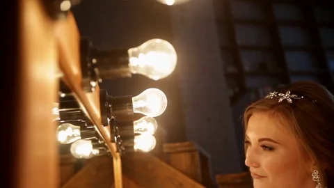 Beautiful bride stands in front of a mirror with lights in a loft interior Stock Footage 69828088