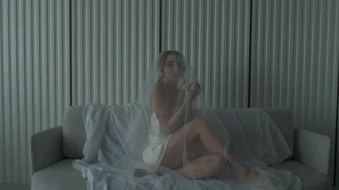 Beautiful bride under a veil sits on a sofa Vidéo 219629378