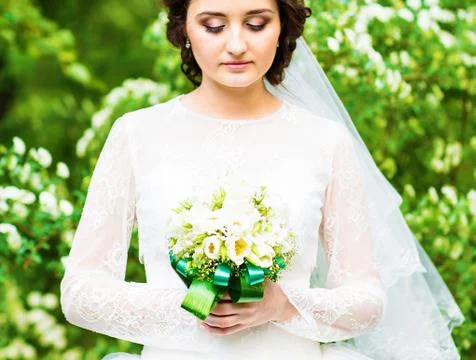 Beautiful bride with wedding bouquet of flowers outdoors in spring  park Stock Photos