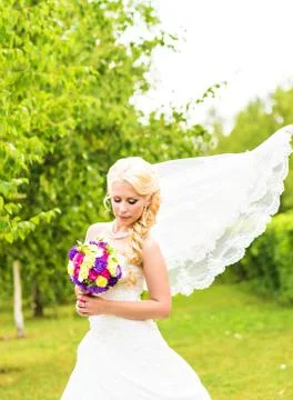 Beautiful bride with wedding bouquet of flowers outdoors in green park Stock Photos