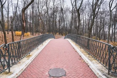 Beautiful bridge lined with red bricks with a figured metal fence Stock Photos
