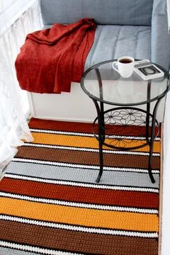 Beautiful bright balcony interior with striped carpet and grey sofa Stock Photos