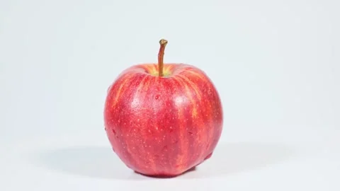 Beautiful bright red apple with drops of water rotates on white background. Clos Stock-Footage 247177532