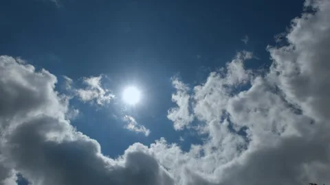 Beautiful bright sun shining through white clouds in blue sky Stock Footage 328361349