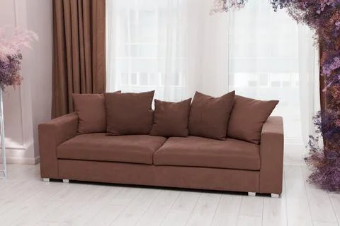 Beautiful brown sofa with five pillows, forms part of interior furniture in.. Stock Photos