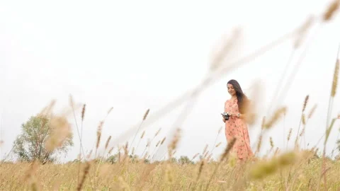Beautiful brunette with a camera. Dress develops in the wind. Slow motion. Green Stock Footage 102598643