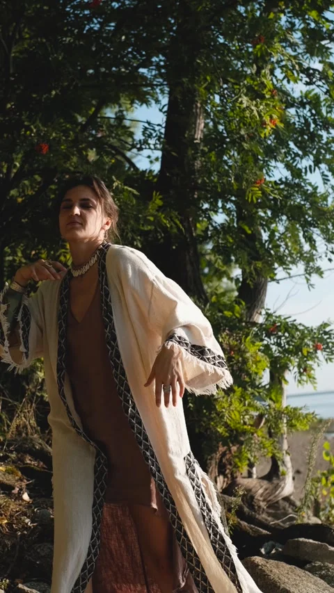 A beautiful brunette dressed in boho style meditates and dances in the forest. A Video stock 320560526