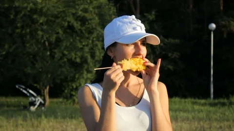 Beautiful brunette eats corn, looks into the camera Stock Footage 111204264