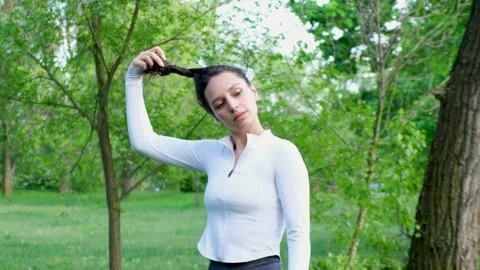 A beautiful brunette lets down her long hair in the park. Slow motion Stock Footage 275075450