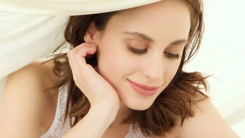 Beautiful brunette moving under bed sheets Stock Footage 87329800