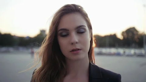 Beautiful brunette posing by the camera, stroking hair, smiling brightly.  Stock Footage 82323649
