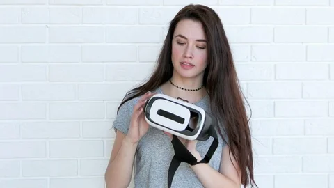 Beautiful brunette puts on virtual reality glasses 스톡 동영상 74468017