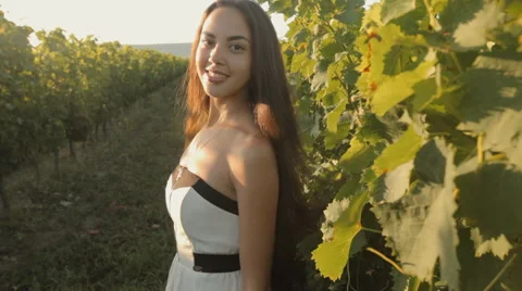 Beautiful brunette in a strapless dress posing next to the vine Stock Footage 59384039