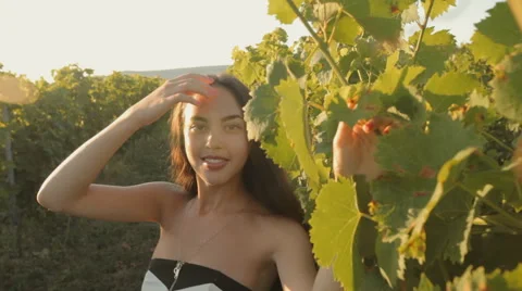 Beautiful brunette in a strapless dress posing next to the vine Stock Footage 59387459