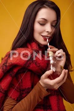 Beautiful brunette woman with big red knitted scarf drinking a hot tea Stock Photos