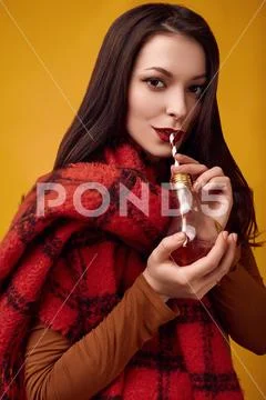 Beautiful brunette woman with big red knitted scarf drinking a hot tea Stock Photos