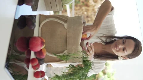 Beautiful brunette woman disassembling a bag of farm vegetables and fruits in Stock Footage 286698567