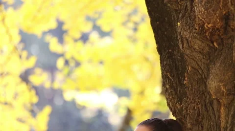 Beautiful brunette woman leaning against a tree and singing Stock Footage 59556579