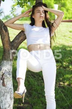 Beautiful brunette woman posing against summer park, bright sunny weather Stock Photos
