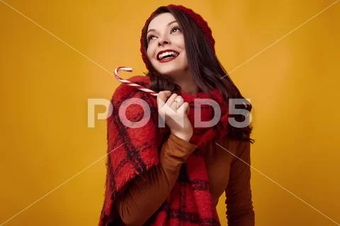 Beautiful brunette woman in red hat with big knitted scarf holding a candy Stock Photos