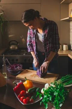 Beautiful brunette working in the kitchen. Woman cuts vegetables. Vegetarian  Stock Photos