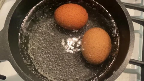 Beautiful bubbles in boiling water in pot with 2 eggs Stock Footage 240905288