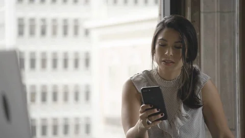 Beautiful businesswoman using her mobile phone near the window Stock Footage