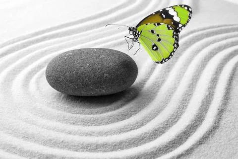 Beautiful butterfly and stone on white sand with pattern. Zen concept Stock Photos