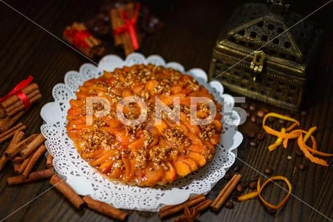 A beautiful cake on a white napkin, surrounded by cinnamon sticks and orange Stock Photos