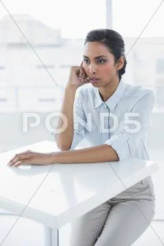 Beautiful calm businesswoman sitting thoughtful at desk Stock Photos