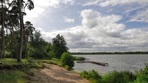 Beautiful, calm lake with small beach and old bridge. Stock Footage