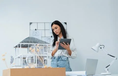 Beautiful caucasian architect using tablet to check house model. Immaculate. Stock Photos