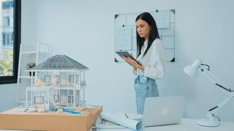 Beautiful caucasian architect using tablet to check house model. Immaculate. 스톡 사진