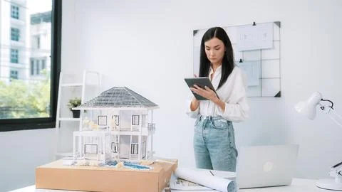Beautiful caucasian architect using tablet to check house model. Immaculate. 写真素材