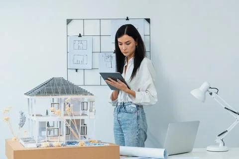 Beautiful caucasian architect using tablet to check house model. Immaculate. 写真素材