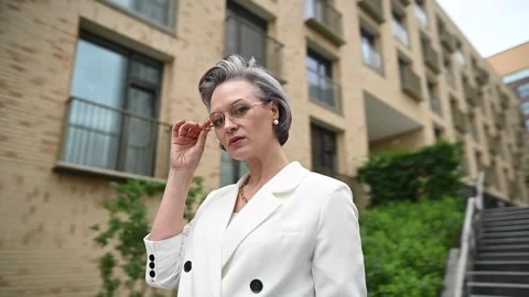 Beautiful caucasian elderly gray-haired business woman takes off her glasses Video stock 253466011