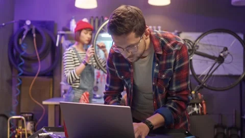 Beautiful caucasian young man using laptop online shopping for bike parts and Stock Footage 232867358