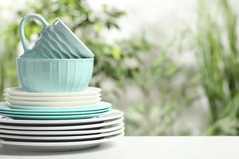 Beautiful ceramic dishware and cup on white table outdoors, space for text Stock Photos