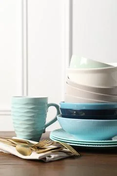 Beautiful ceramic dishware, cup and cutlery on wooden table Stock Photos