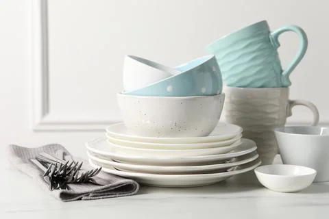 Beautiful ceramic dishware, cups and cutlery on white marble table Stock Photos