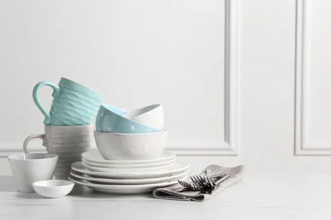 Beautiful ceramic dishware, cups and cutlery on white marble table, space f.. Stock Photos