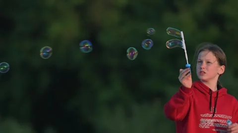 Beautiful child is blowing soap bubbles. Slow motion. Stock Footage 339778119