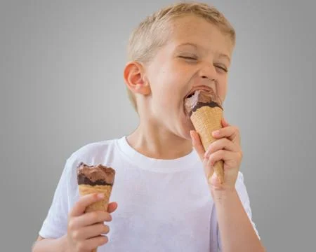 Beautiful child boy eats ice cream on a stick Photos