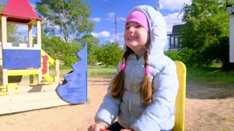 Beautiful child wearing a spring jacket and hat rides on balancing swing . Littl Stock Footage 277549390